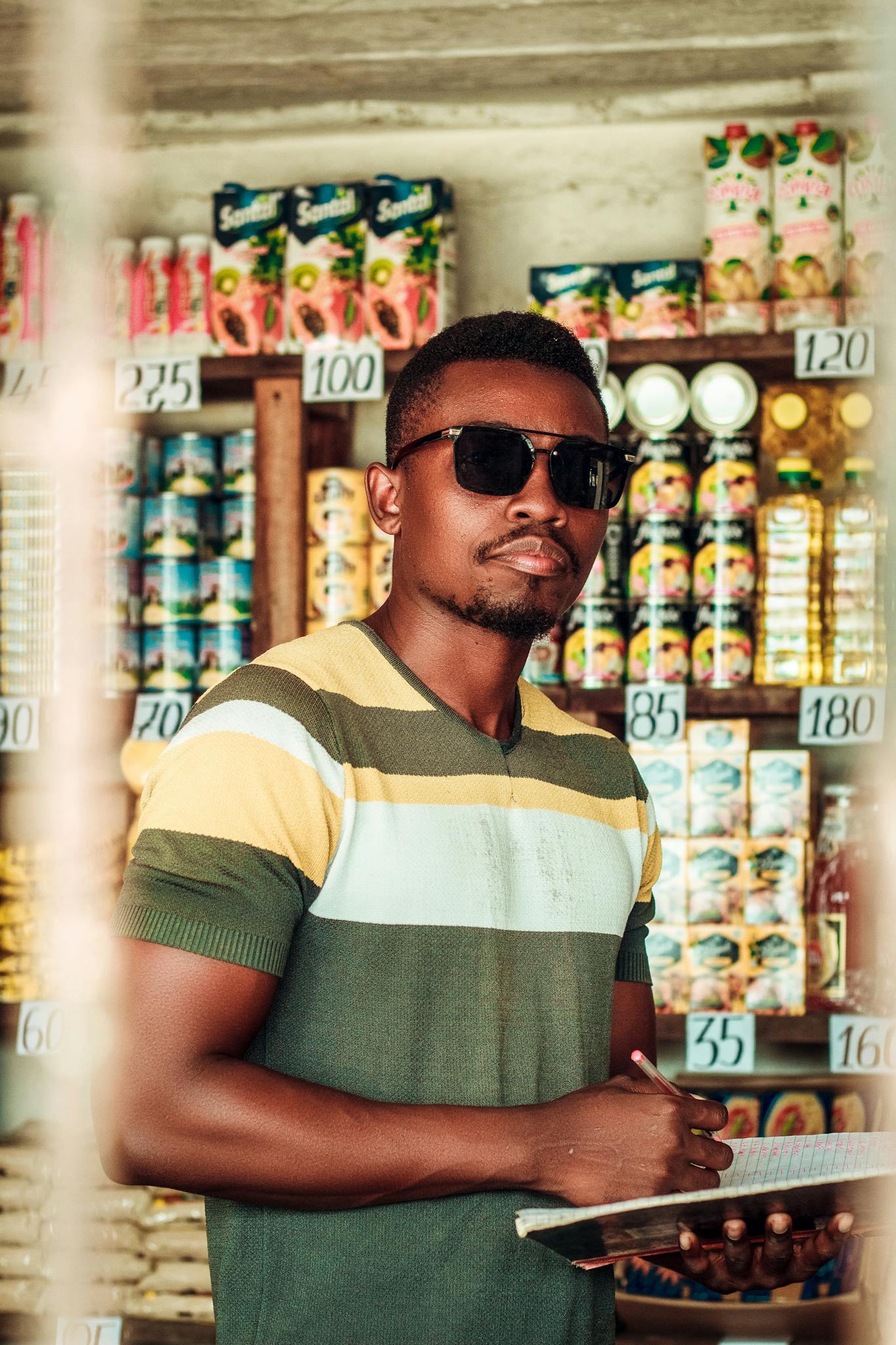 Man with sunglasses writing on a clipboard in a grocery store in Nampula, Mozambique.